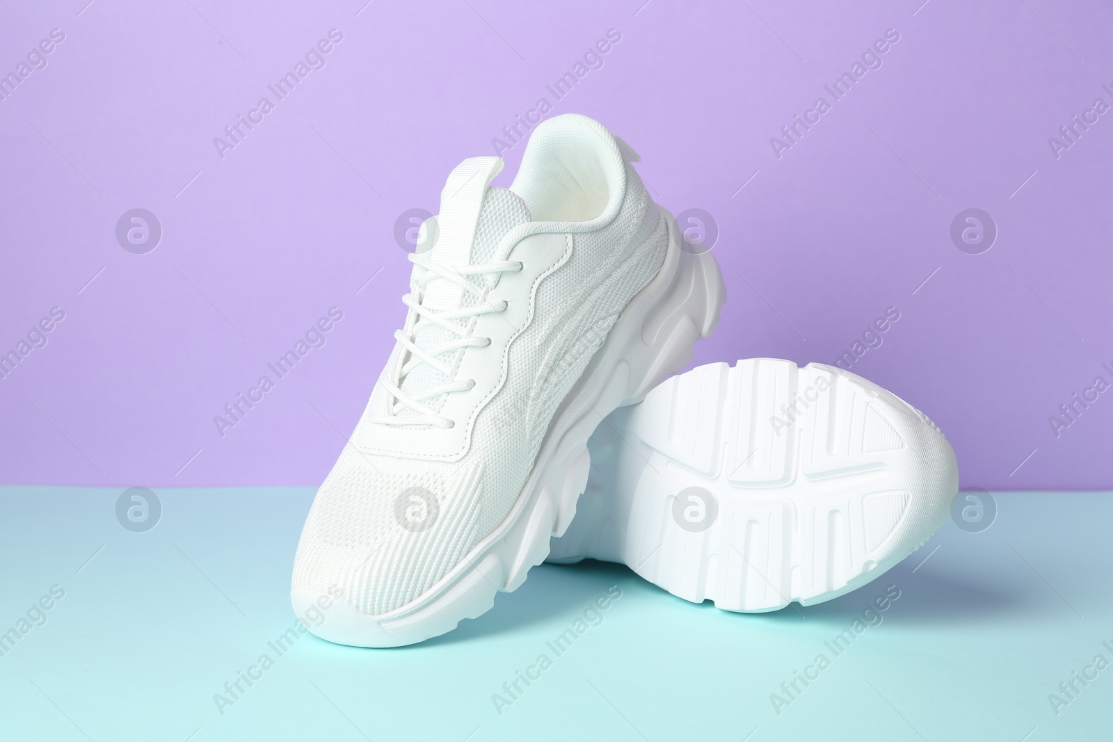 Photo of Pair of stylish white sneakers on color background