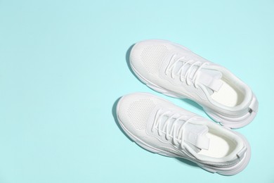 Photo of Pair of stylish white sneakers on light blue background, top view. Space for text