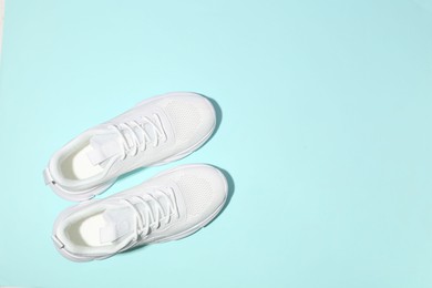 Photo of Pair of stylish white sneakers on light blue background, top view. Space for text