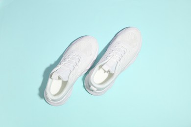 Photo of Pair of stylish white sneakers on light blue background, top view