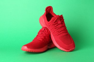 Photo of Pair of stylish red sneakers on green background