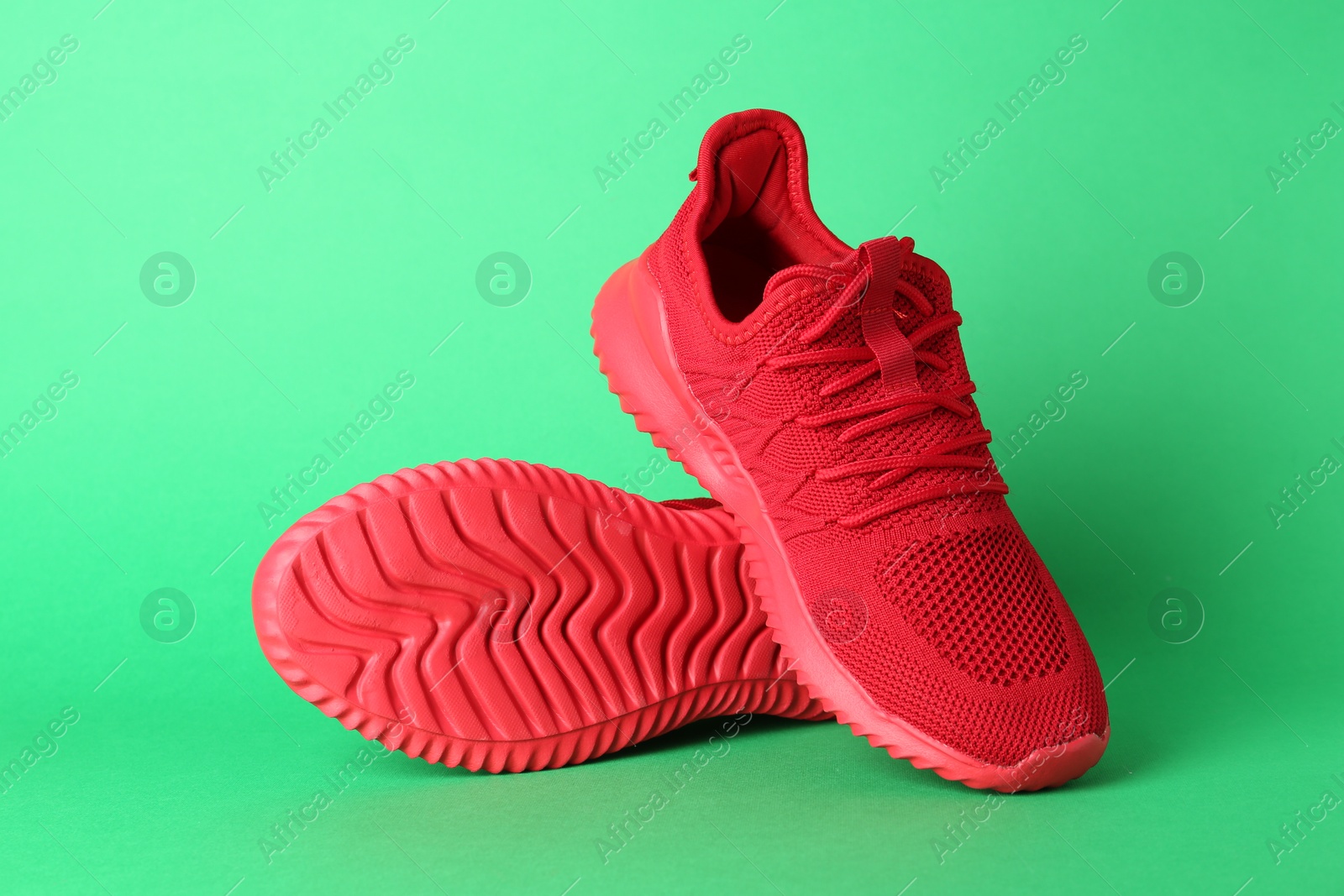 Photo of Pair of stylish red sneakers on green background