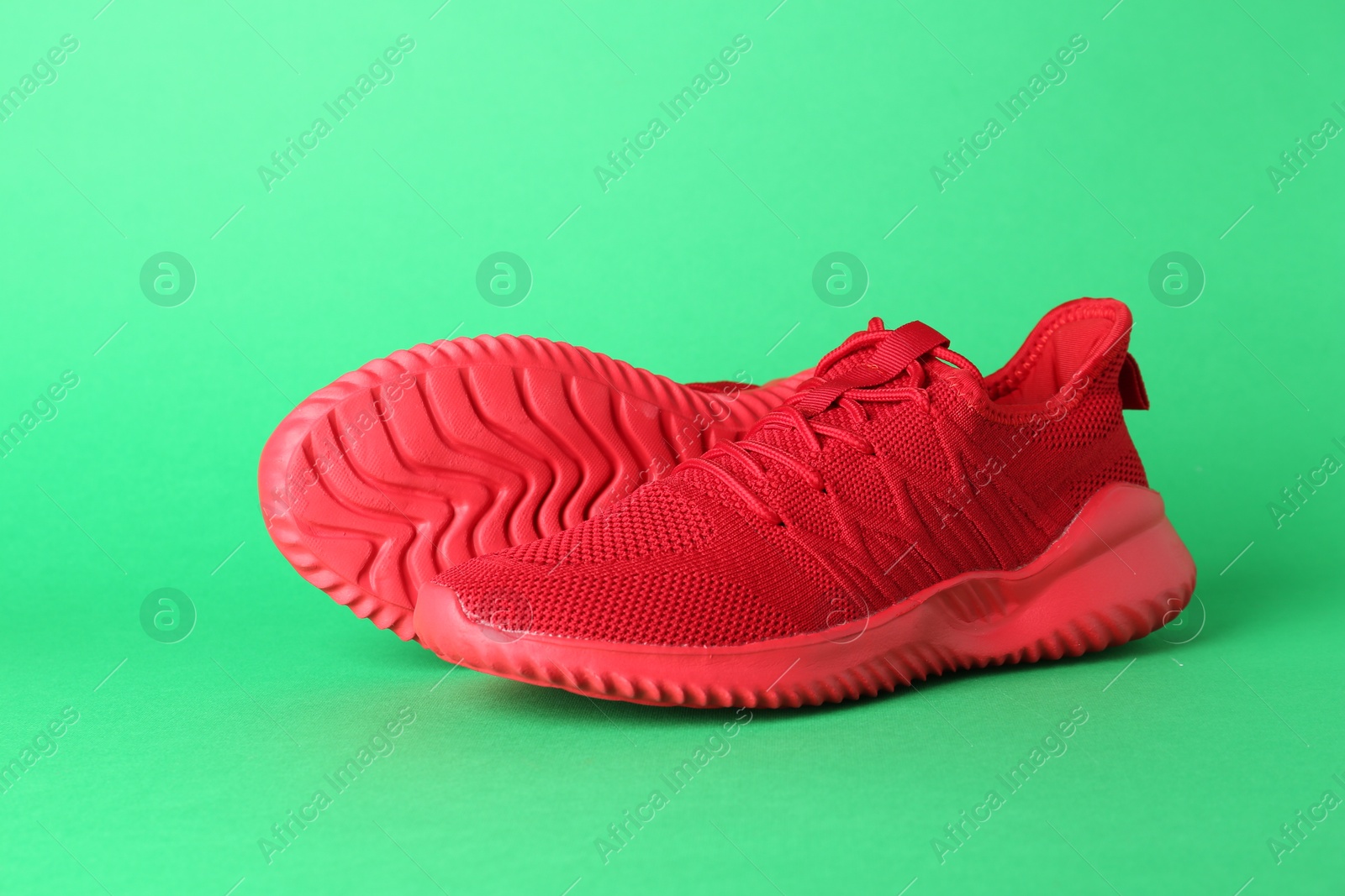 Photo of Pair of stylish red sneakers on green background