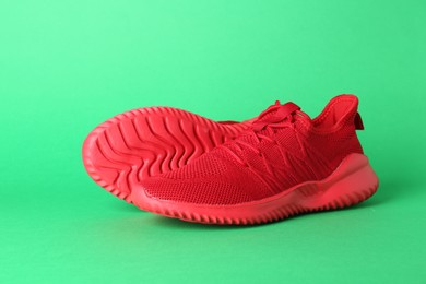 Photo of Pair of stylish red sneakers on green background