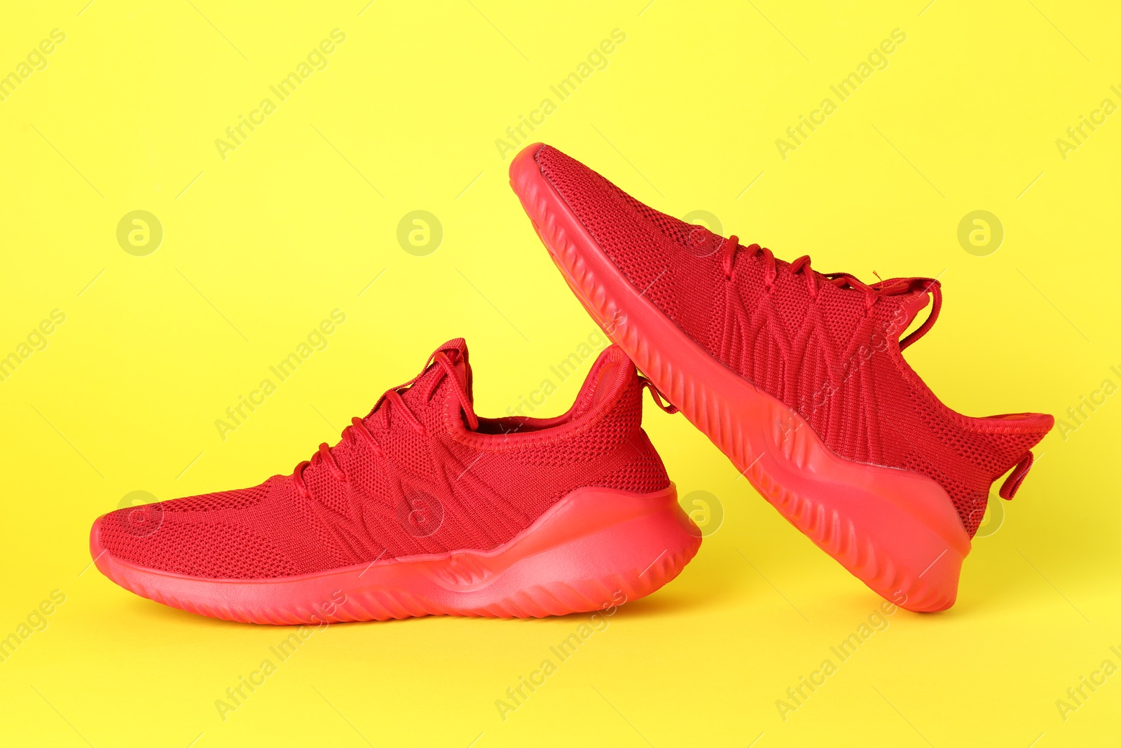 Photo of Pair of stylish red sneakers on yellow background