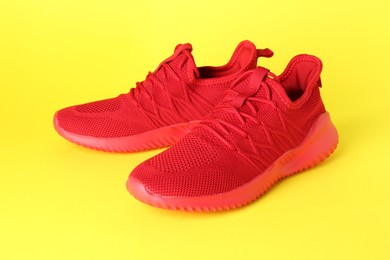 Photo of Pair of stylish red sneakers on yellow background