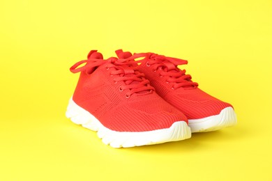 Photo of Pair of stylish red sneakers on yellow background