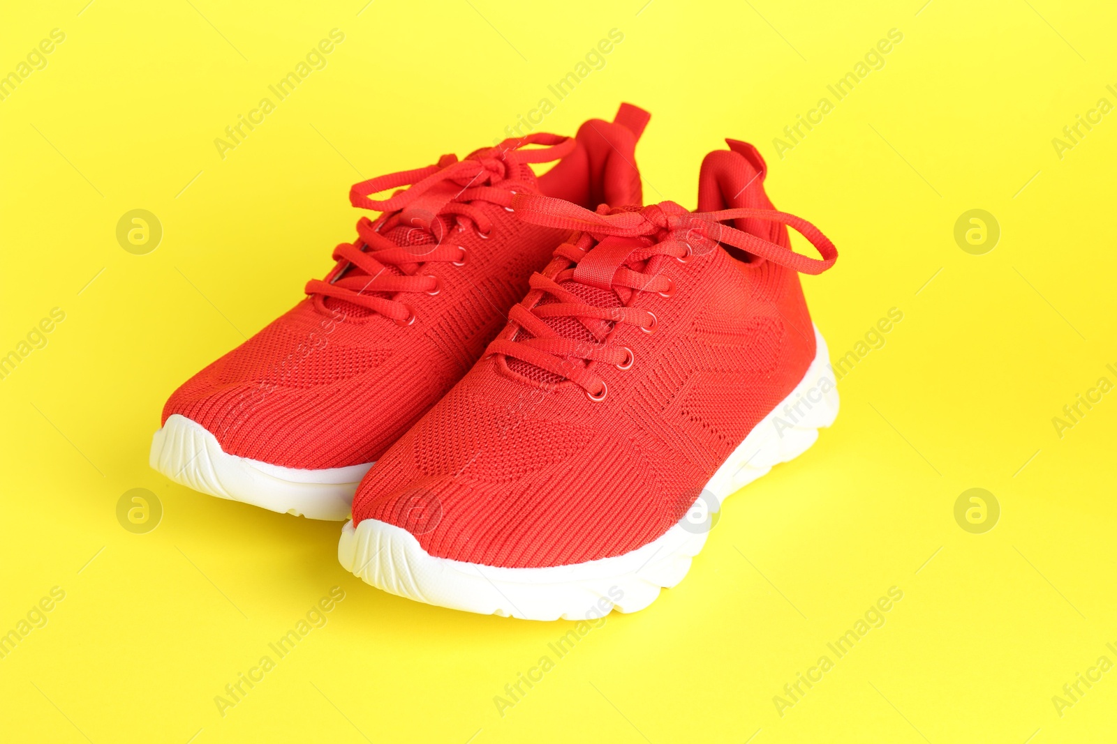 Photo of Pair of stylish red sneakers on yellow background