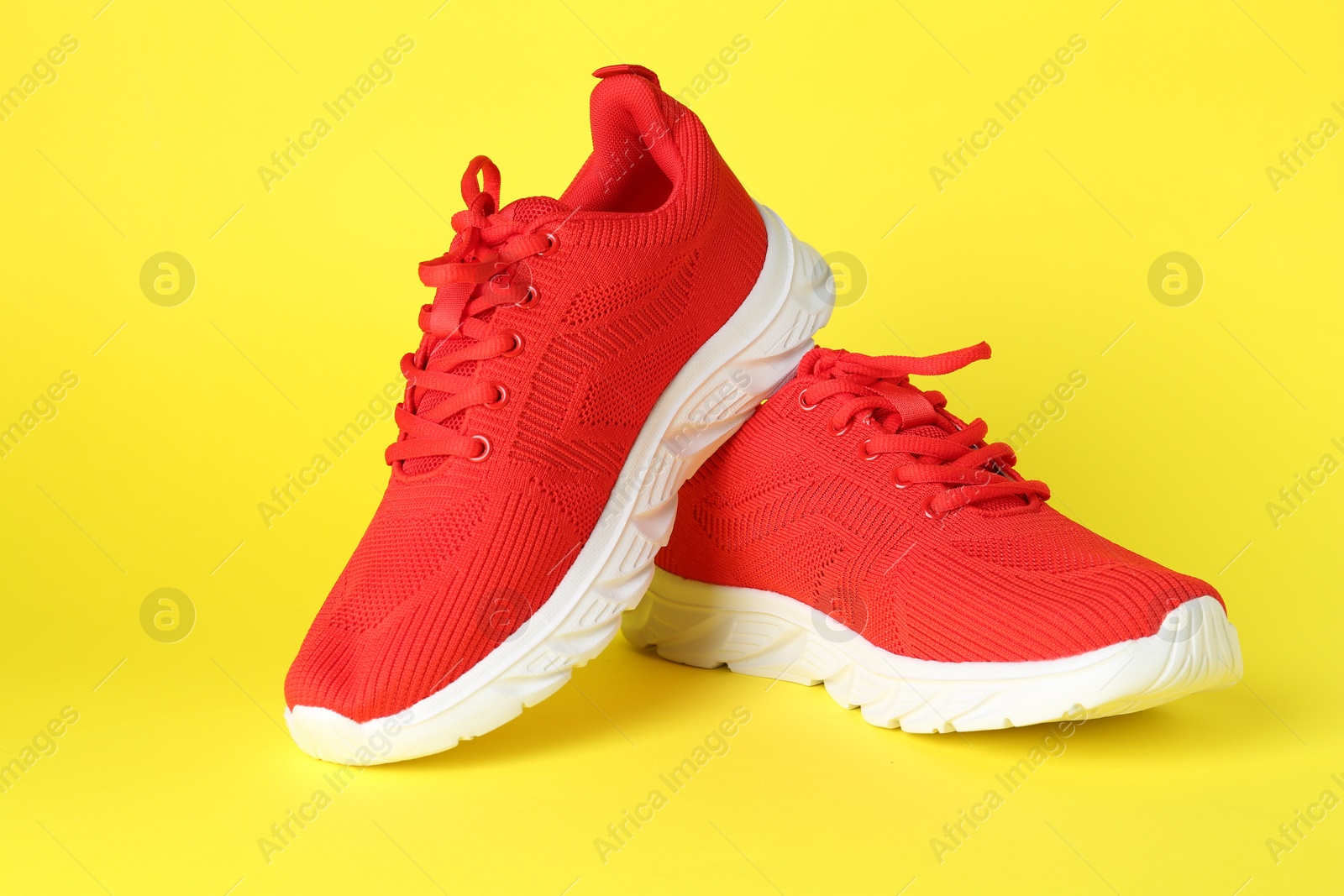 Photo of Pair of stylish red sneakers on yellow background