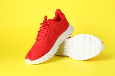 Photo of Pair of stylish red sneakers on yellow background