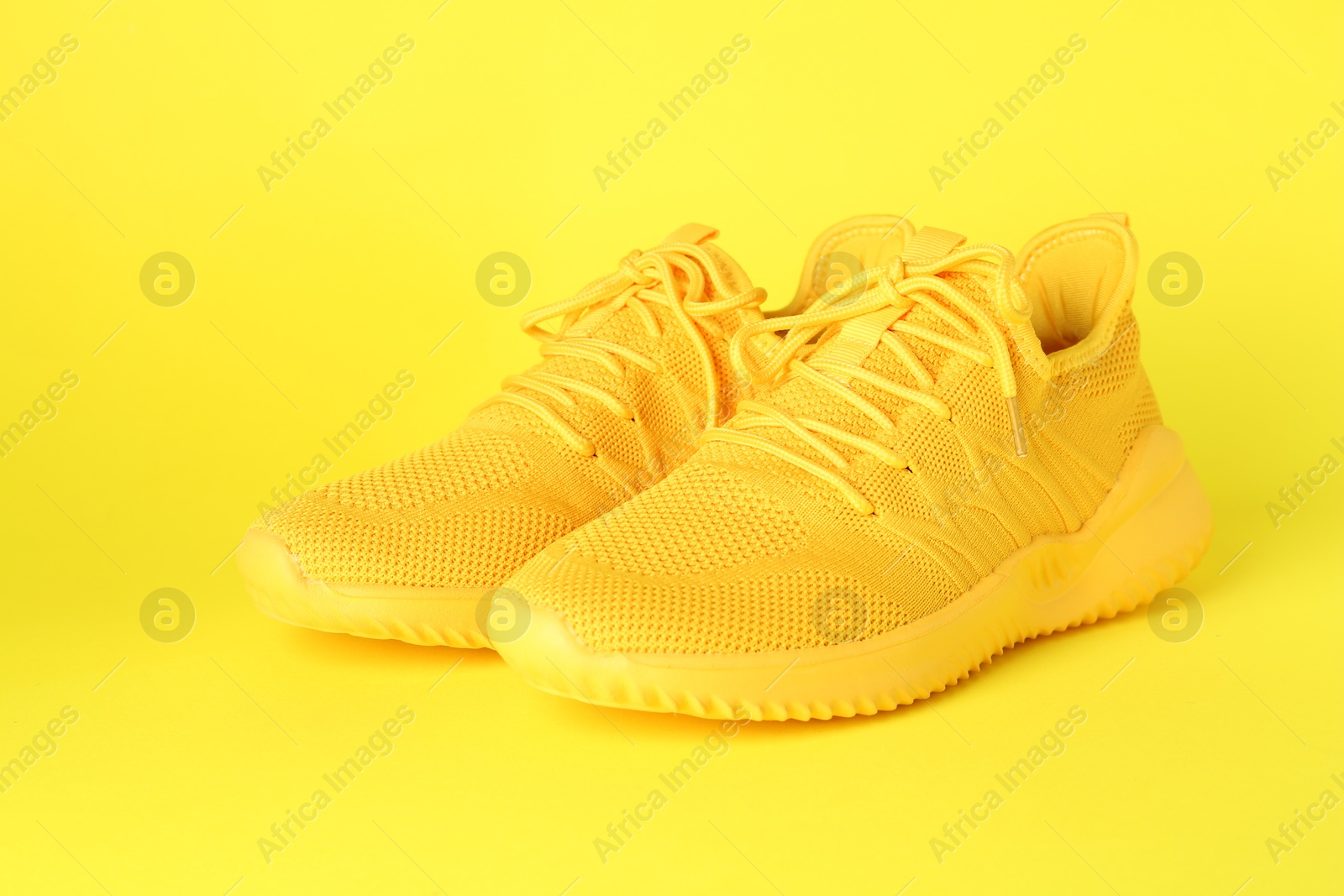 Photo of Pair of stylish sneakers on yellow background