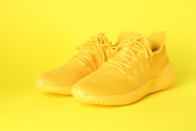 Photo of Pair of stylish sneakers on yellow background