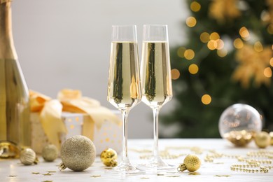 Photo of Champagne in glasses and Christmas decor on white wooden table against blurred lights. Bokeh effect