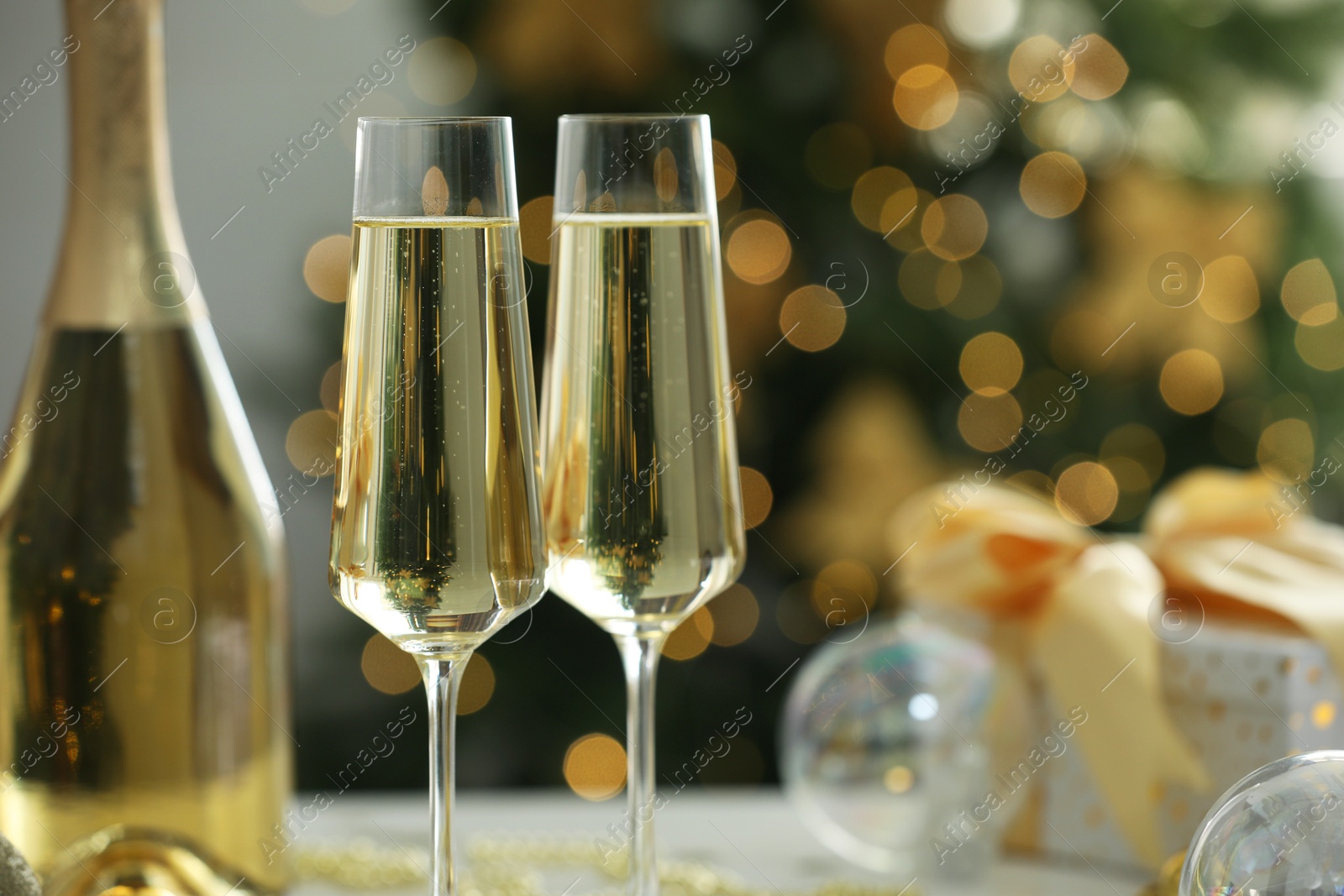 Photo of Champagne in glasses with decor against blurred Christmas lights, closeup and space for text. Bokeh effect