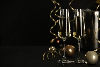 Photo of Champagne in glasses and decor on black table, space or text. Christmas celebration