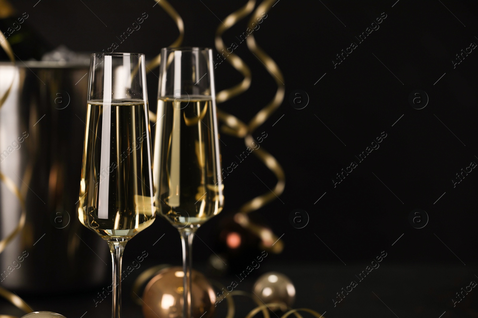 Photo of Champagne in glasses with decor on black table, closeup and space or text. Christmas celebration