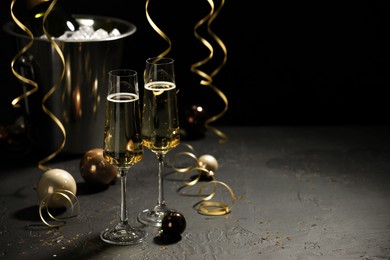 Photo of Champagne in glasses and Christmas decor on grey table, space for text