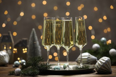 Photo of Champagne in glasses and Christmas decor on wooden table against blurred lights. Bokeh effect