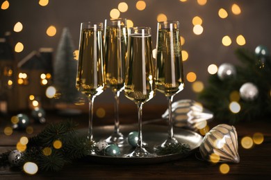 Photo of Champagne in glasses and Christmas decor on wooden table against blurred lights. Bokeh effect