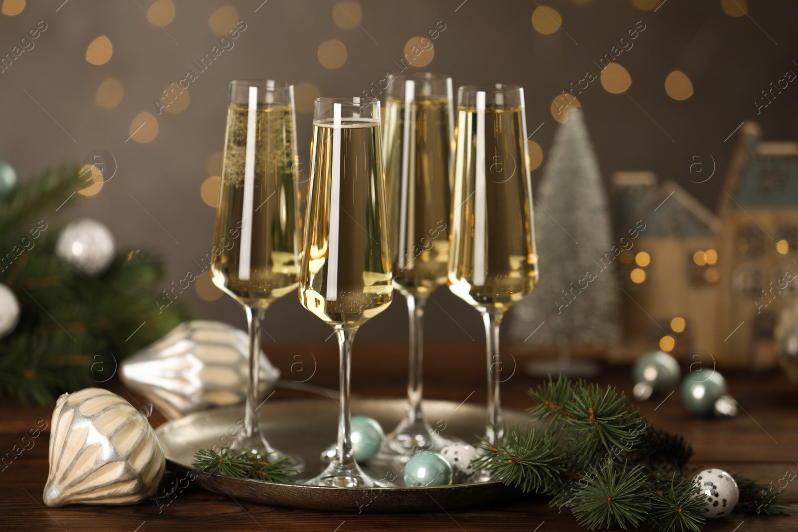 Photo of Champagne in glasses and Christmas decor on wooden table against blurred lights. Bokeh effect