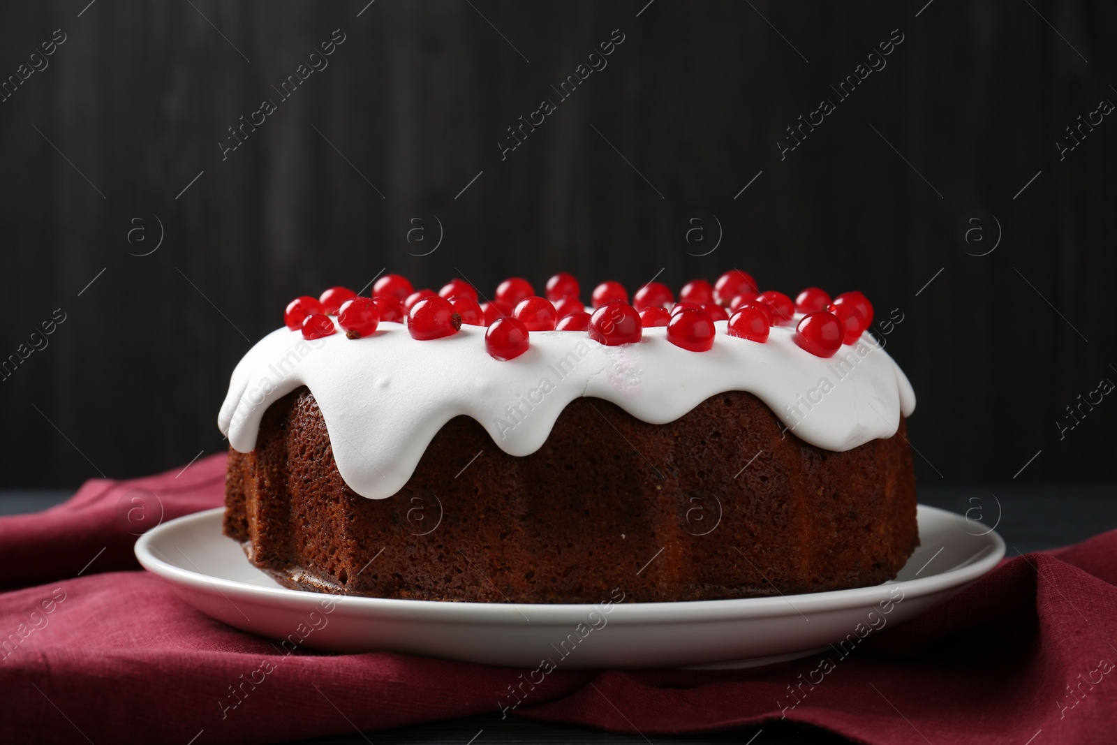 Photo of Tasty Christmas cake with red currants on table against dark background, closeup