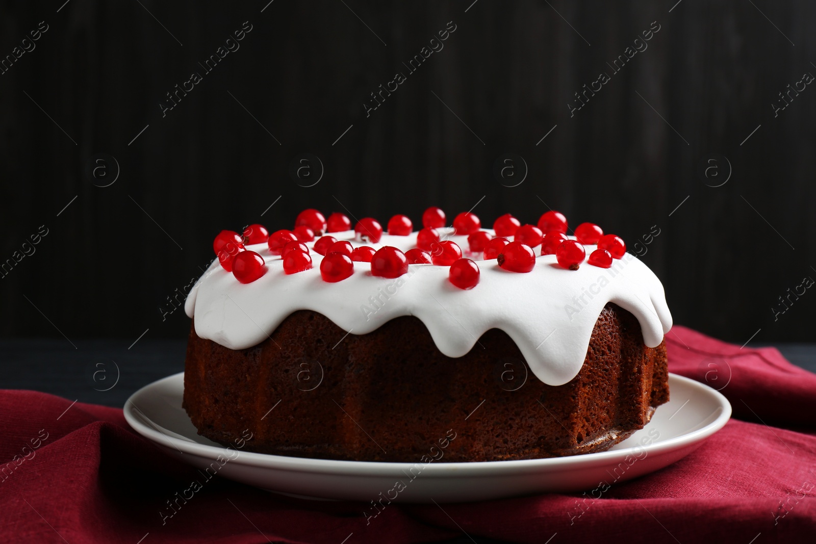 Photo of Tasty Christmas cake with red currants on table against dark background, closeup