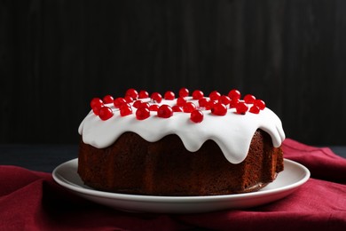 Photo of Tasty Christmas cake with red currants on table against dark background, closeup