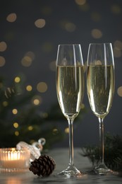 Photo of Delicious champagne in glasses and Christmas decor on marble table against blurred lights, closeup