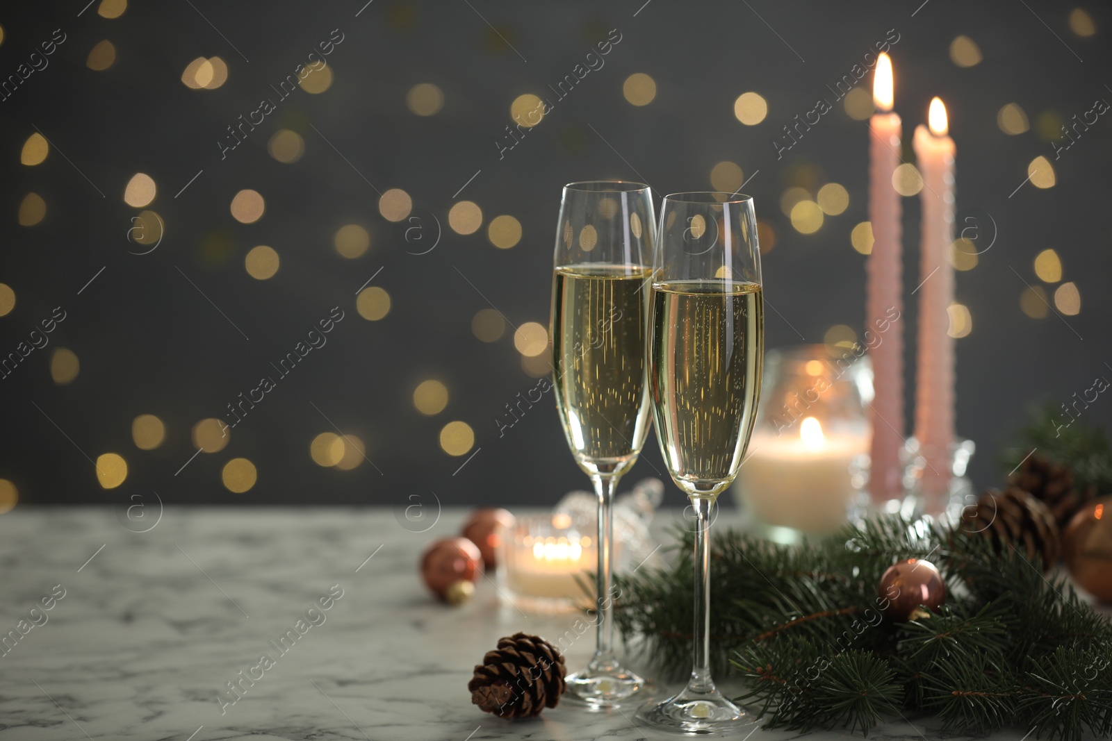 Photo of Delicious champagne in glasses and Christmas decor on marble table against blurred lights, closeup. Space for text