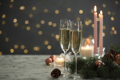 Photo of Delicious champagne in glasses and Christmas decor on marble table against blurred lights, closeup. Space for text