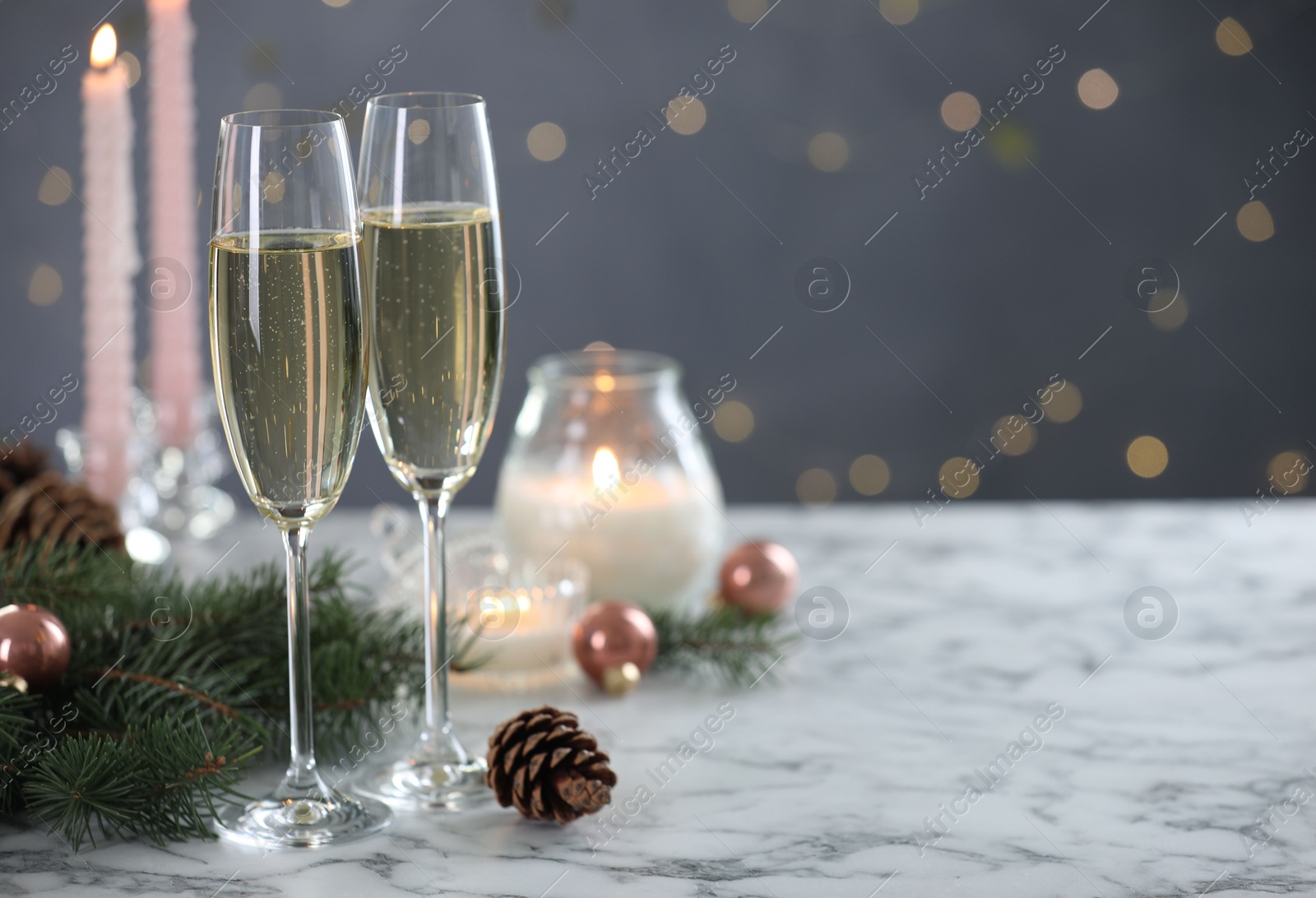 Photo of Delicious champagne in glasses and Christmas decor on marble table against blurred lights, closeup. Space for text