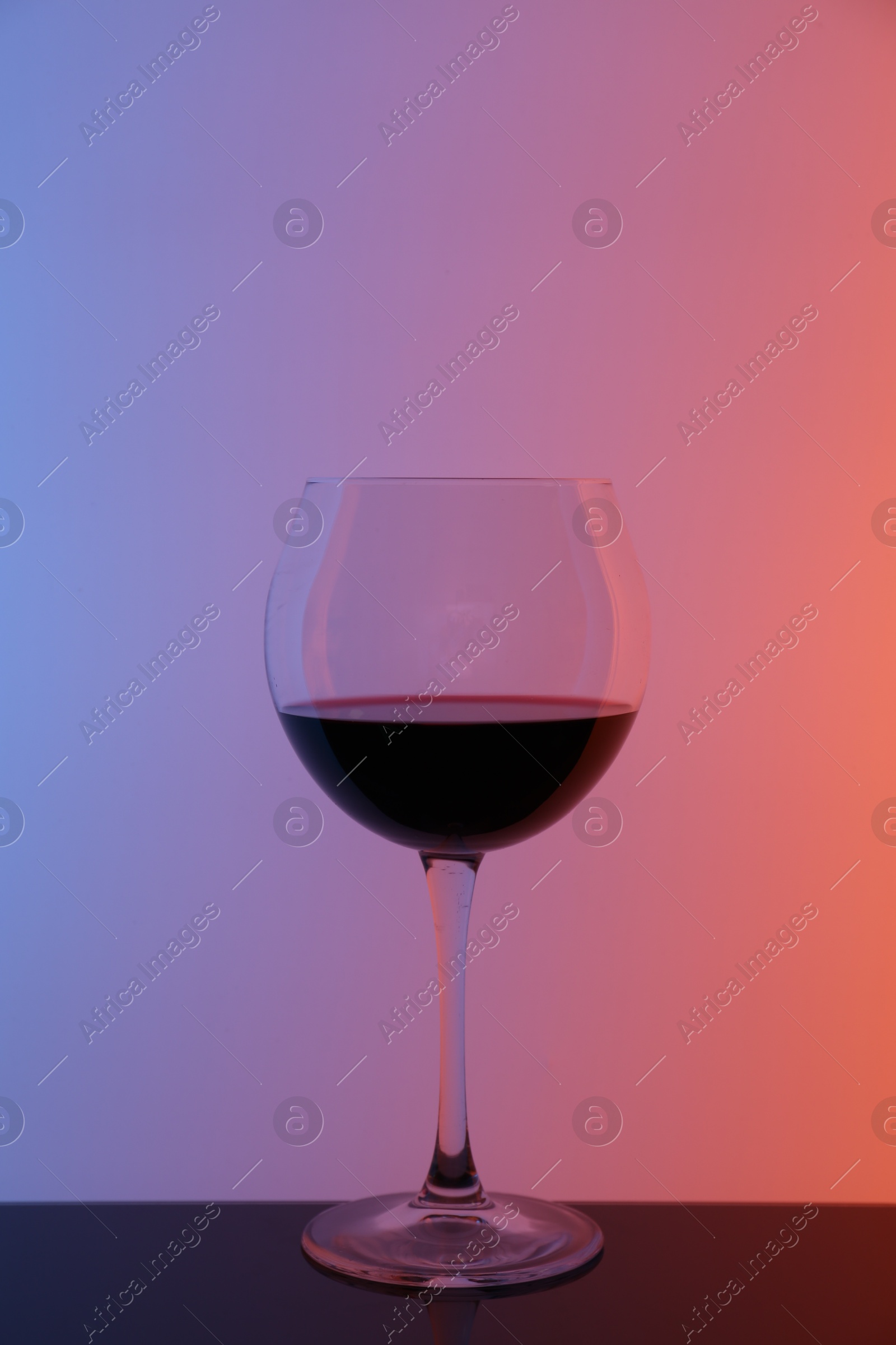 Photo of Glass of wine on table against color background