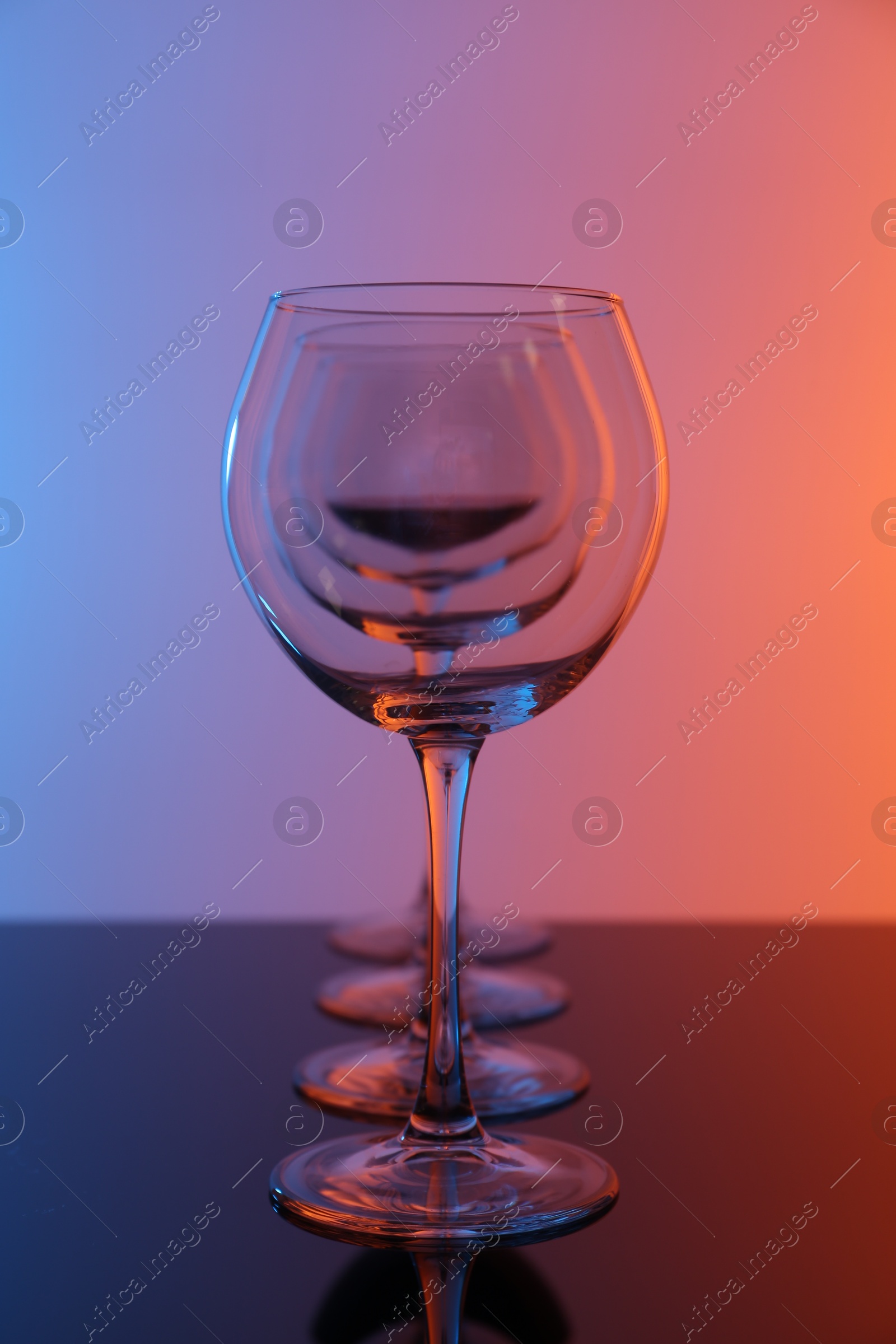 Photo of Wine glasses on table against color background