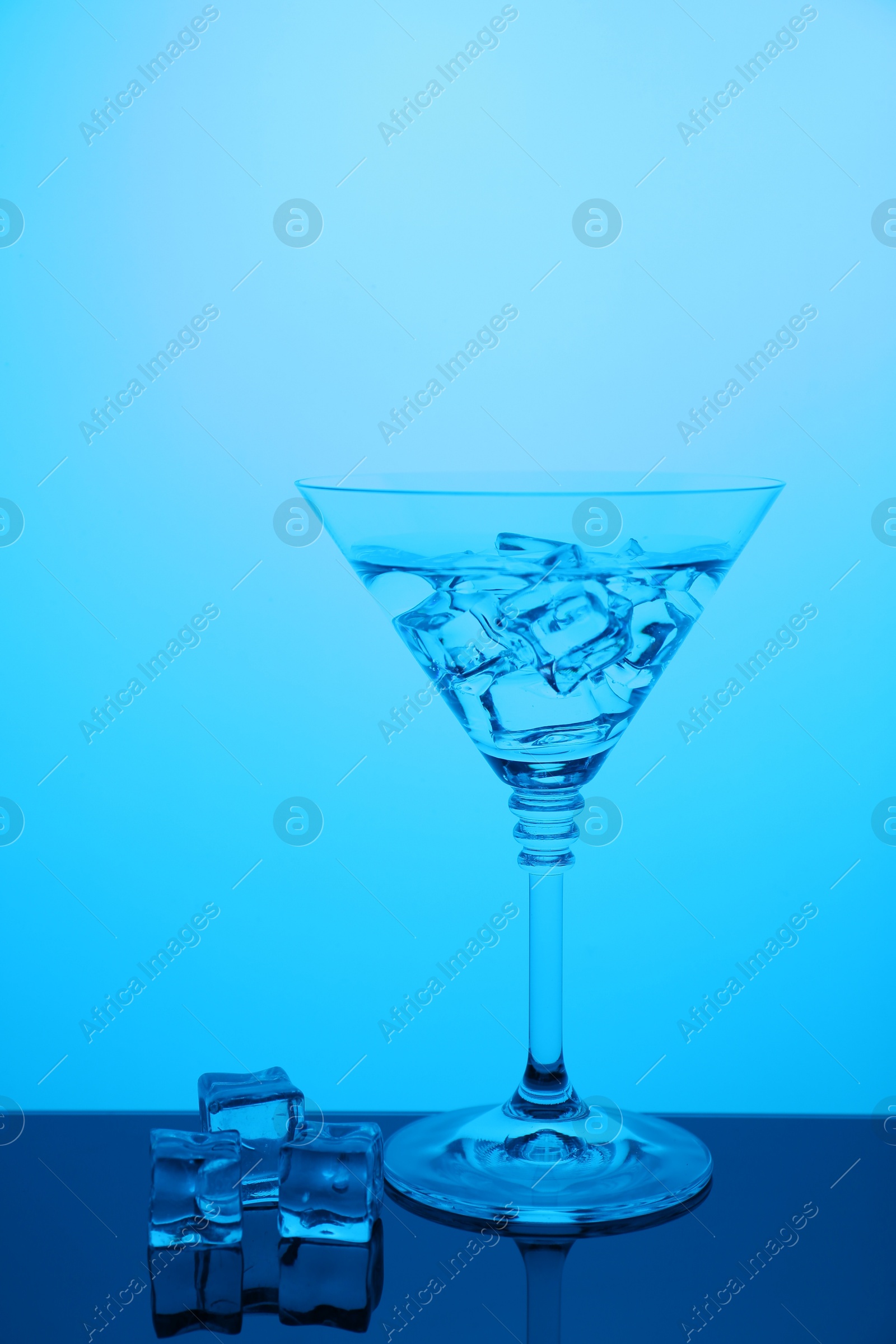 Photo of Cocktail glass with water and ice cubes on table, color tone effect