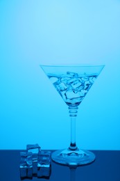 Photo of Cocktail glass with water and ice cubes on table, color tone effect