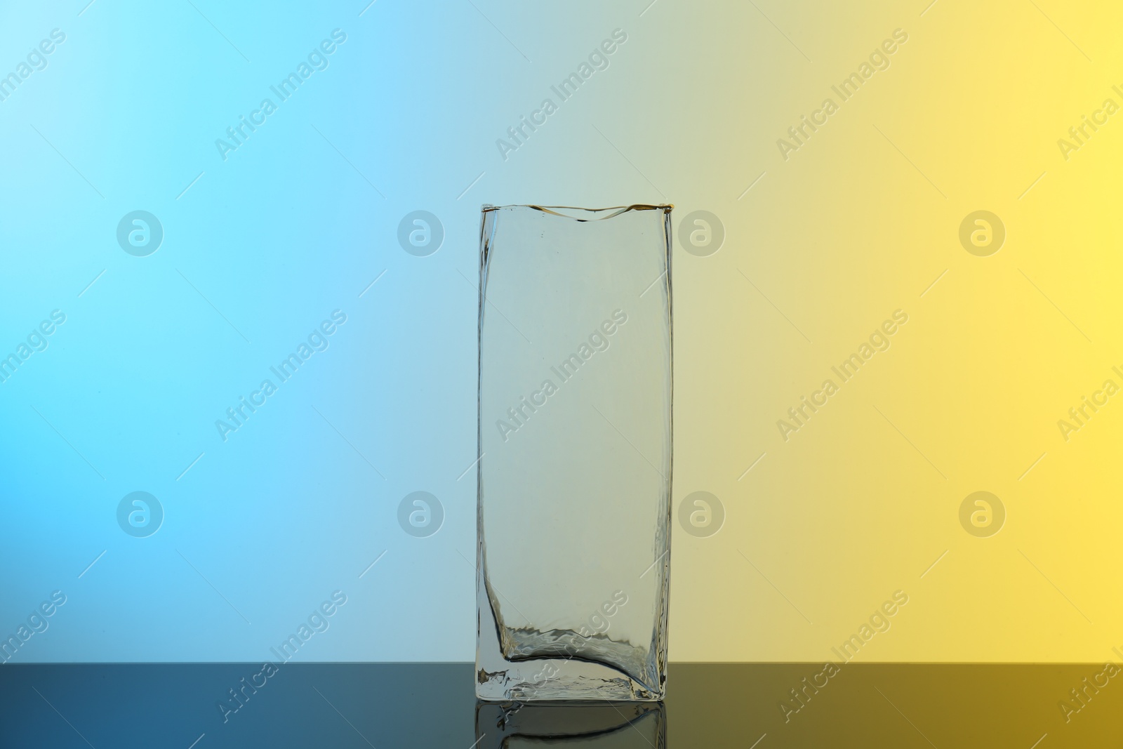 Photo of Glass vase on table against color background