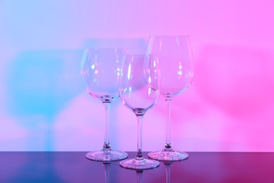 Photo of Empty glasses on table against color background