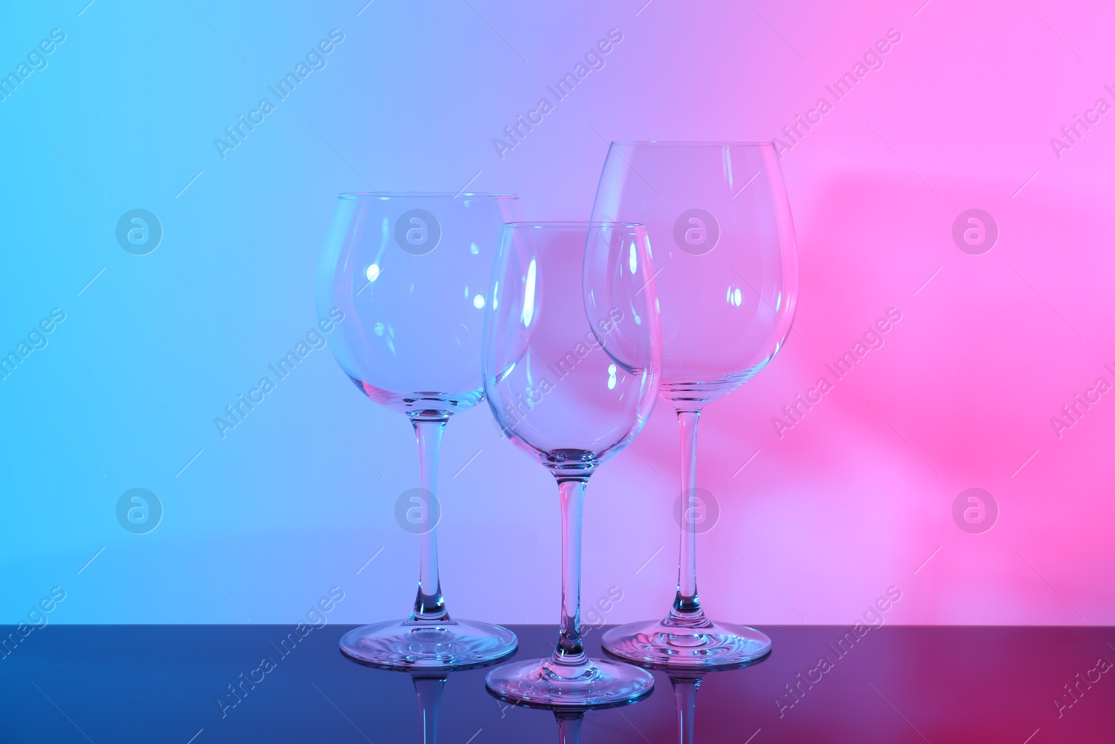 Photo of Empty glasses on table against color background