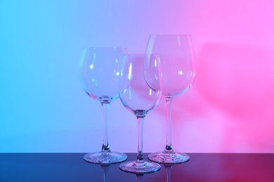 Photo of Empty glasses on table against color background