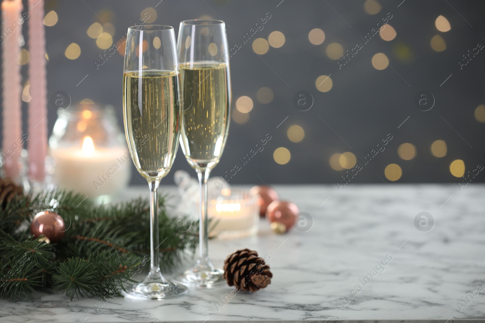 Photo of Delicious champagne in glasses and Christmas decor on marble table against blurred lights, closeup. Space for text