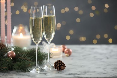 Photo of Delicious champagne in glasses and Christmas decor on marble table against blurred lights, closeup. Space for text