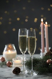 Photo of Delicious champagne in glasses and Christmas decor on marble table against blurred lights