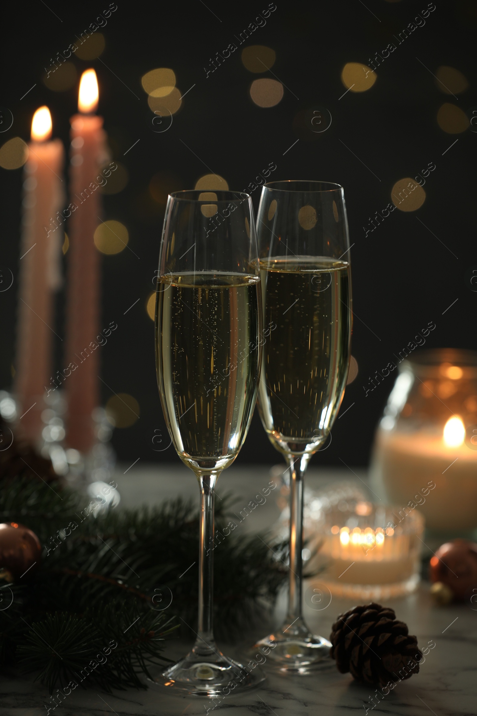 Photo of Delicious champagne in glasses and Christmas decor on marble table against blurred lights, closeup