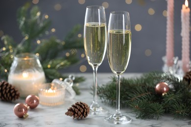 Photo of Delicious champagne in glasses and Christmas decor on marble table against blurred lights, closeup