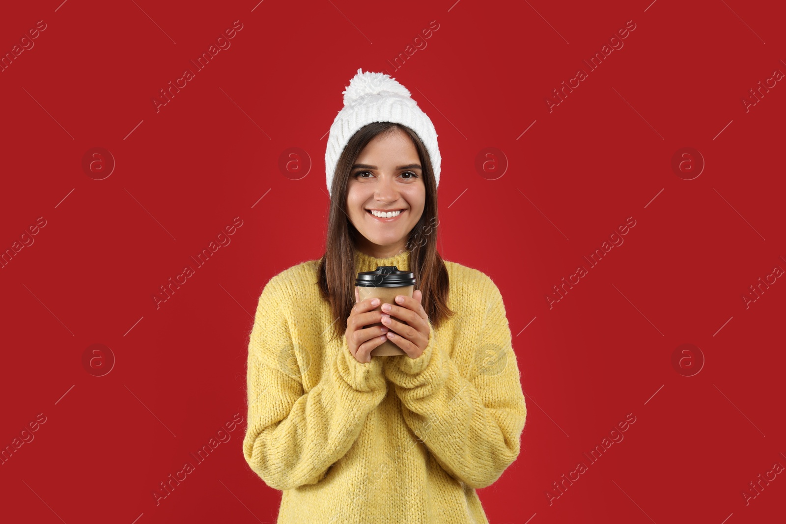 Photo of Happy beautiful woman with paper cup of mulled wine on red background