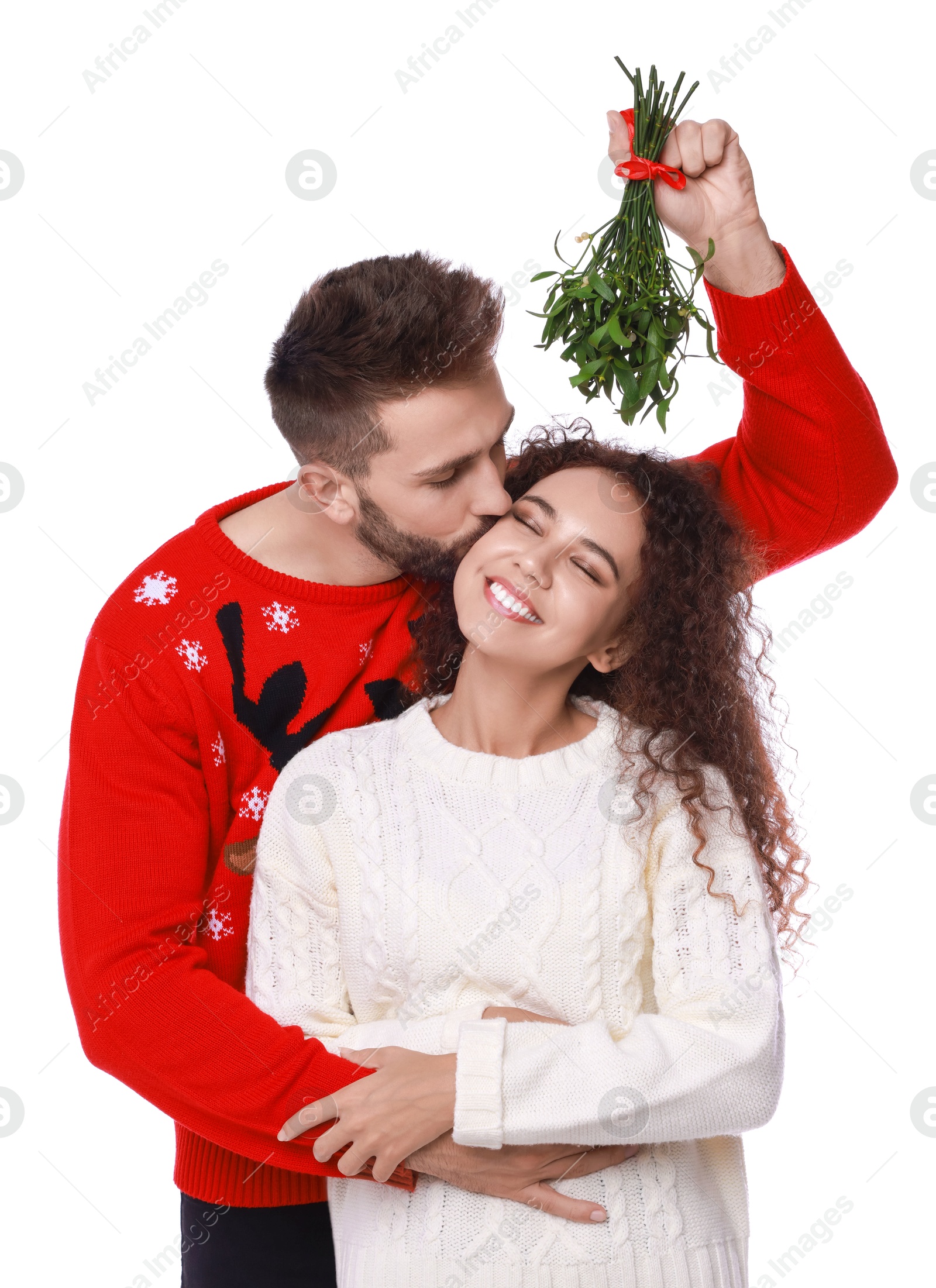 Photo of Happy man kissing his girlfriend under mistletoe bunch on white background