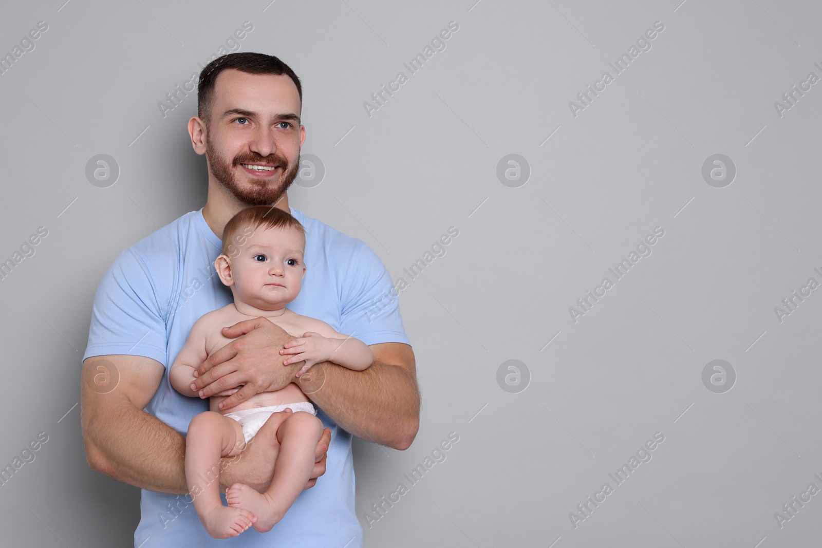 Photo of Father with his cute baby on grey background, space for text