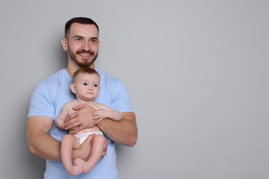 Photo of Father with his cute baby on grey background, space for text