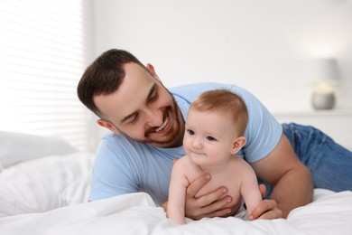 Photo of Father with his cute baby on bed at home