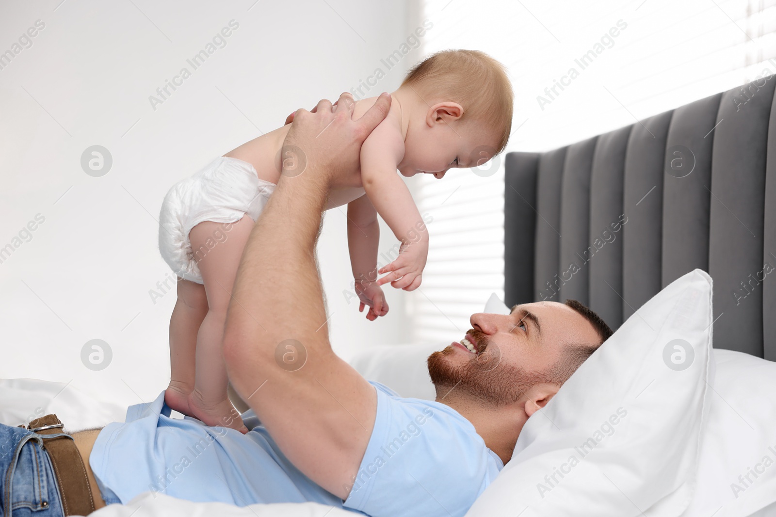 Photo of Father with his cute baby on bed at home